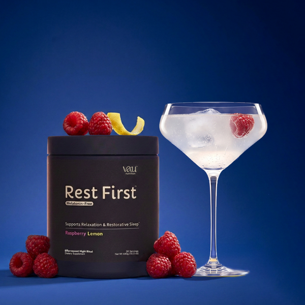 Rest First Sleep Magnesium jar beside a coupe glass of the raspberry lemon drink, with fresh raspberries and lemon peel